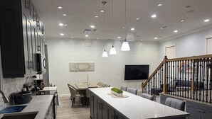 A modern kitchen with a central island, dining area with chairs, and a staircase with a railing. - Sunset cruiser close to Redington Beach (Seminole)