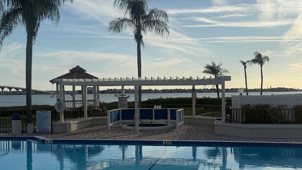 A swimming pool with a gazebo, palm trees, and a view of a bridge. - Close to everything! 1bdr in St. Pete beach (St. Petersburg)
