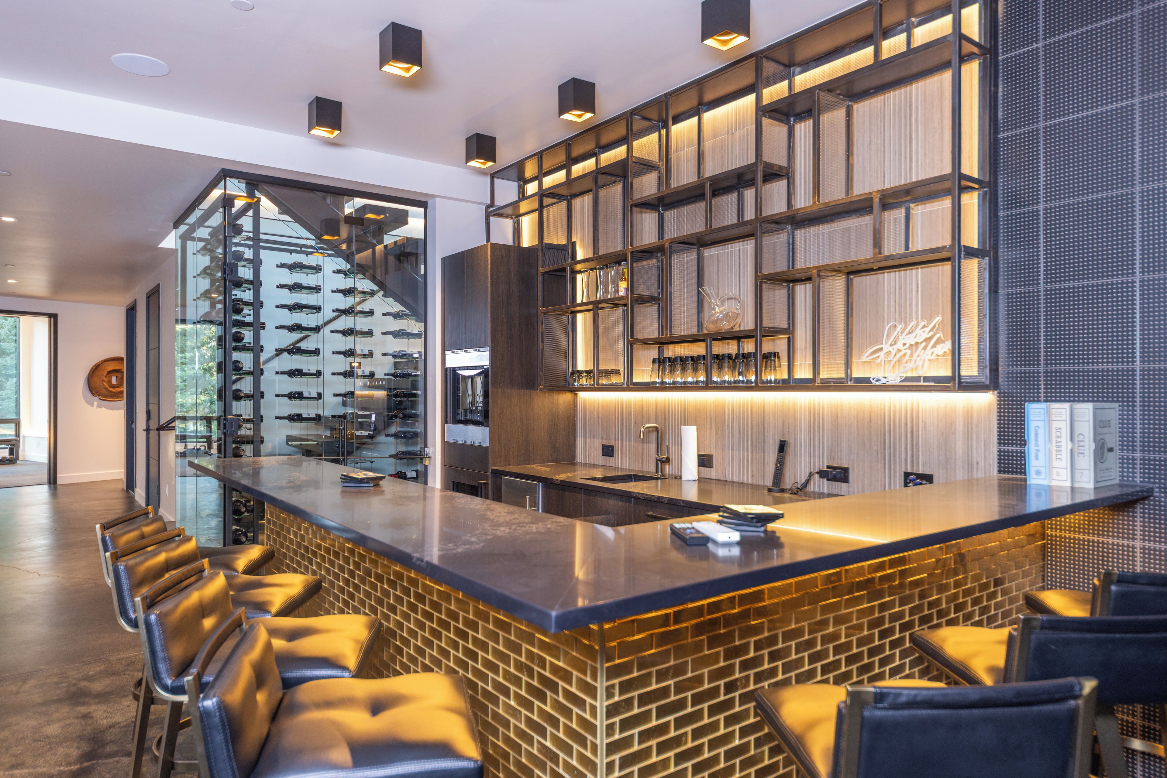 A modern bar area with a brick counter, bar stools, and a wine rack.