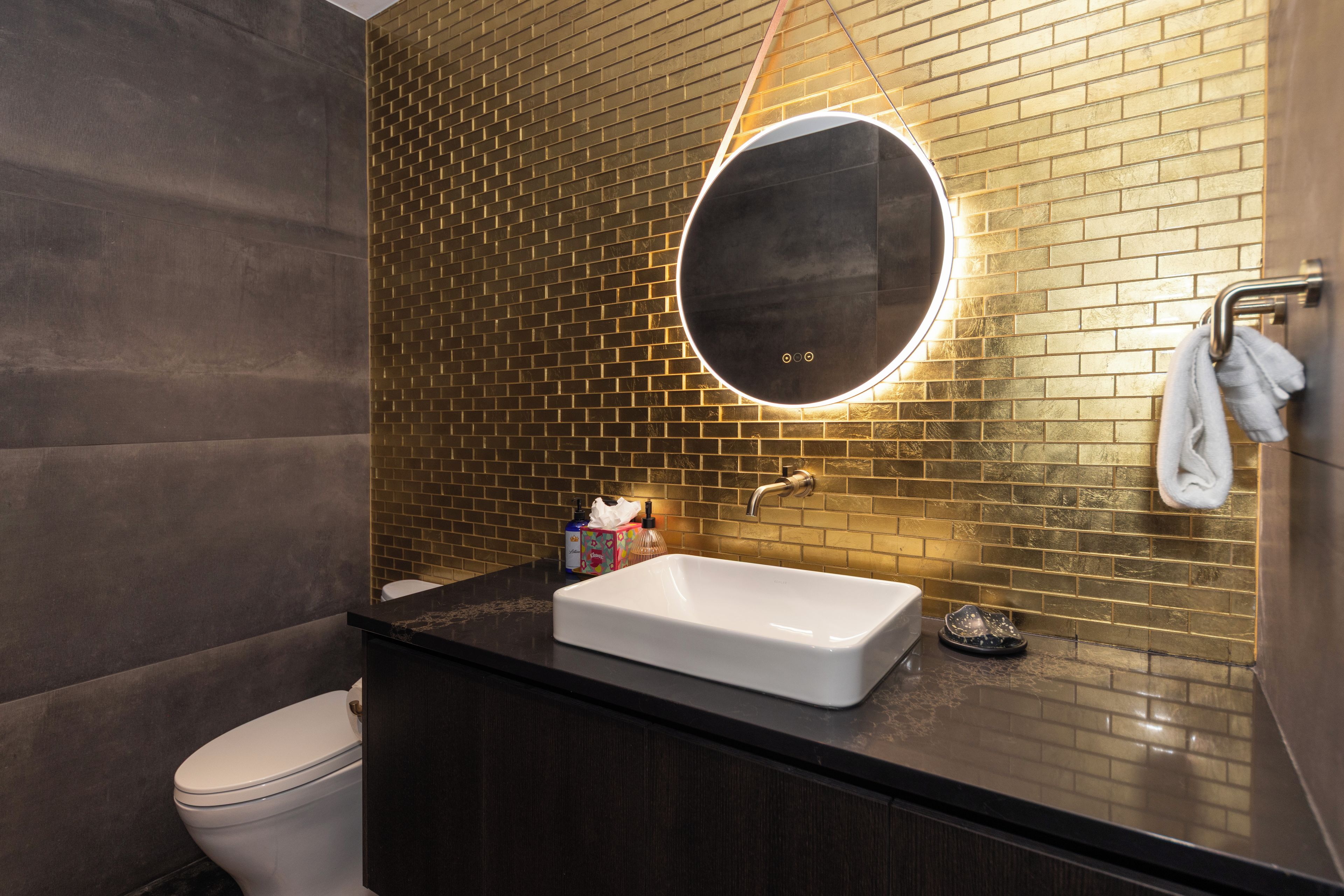 A bathroom with a white sink, a round mirror, and a towel rack.