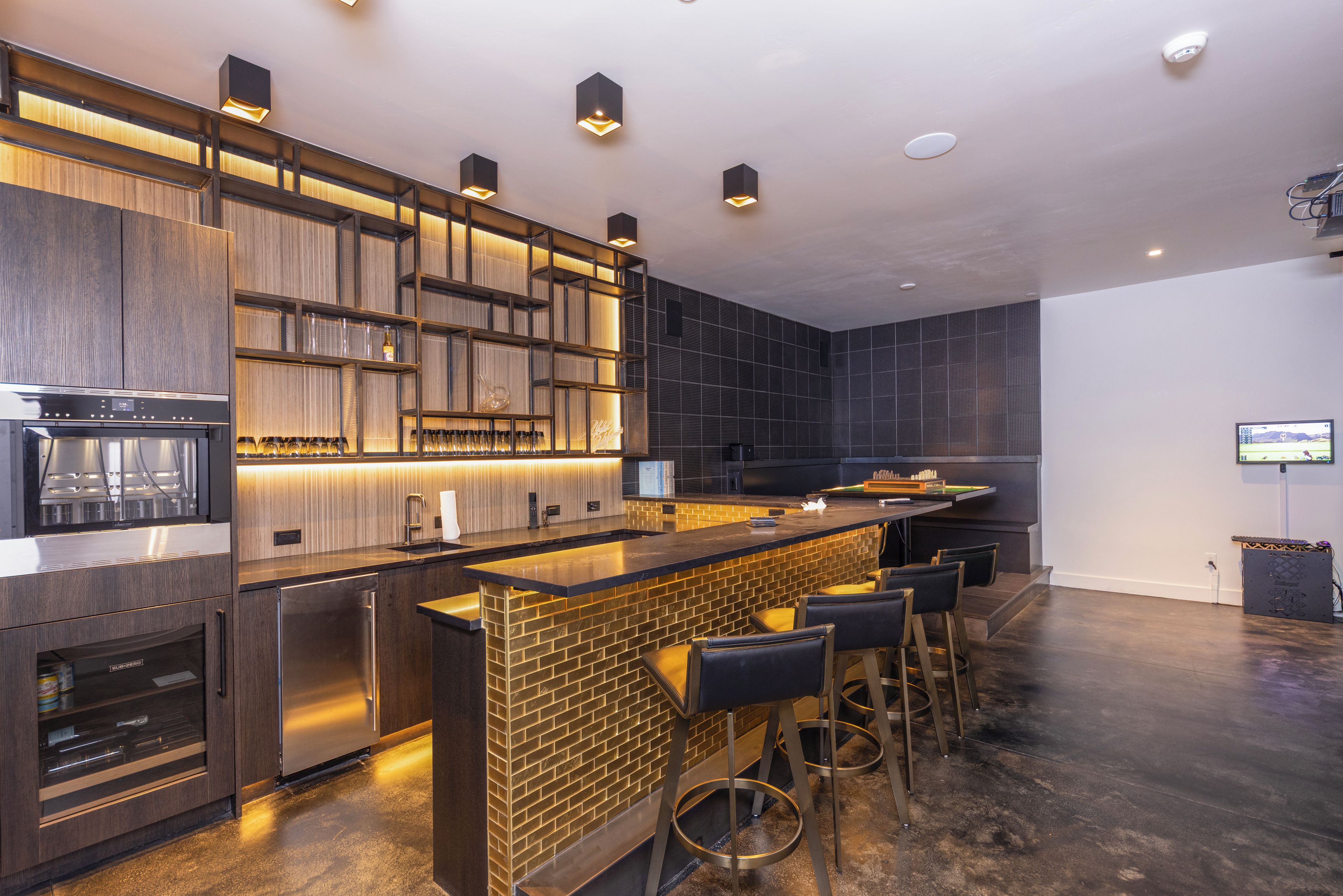 A modern kitchen with a bar area, built-in appliances, and a seating arrangement.