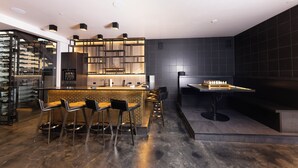 A modern bar area with a wine rack, bar stools, and a chess table. - Steps to slopes; 7,000 sq feet of Luxury, golf simulator, hot tub! (Copper Mountain)