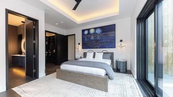 Un dormitorio moderno con una cama grande, un ventilador de techo, un tragaluz y un cuadro de paisaje urbano en la pared.