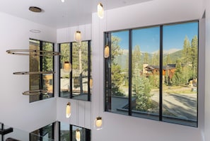 A modern interior with large windows offering a view of a mountainous landscape. - Steps to slopes; 7,000 sq feet of Luxury, golf simulator, hot tub! (Copper Mountain)