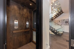 An elevator with a wooden wall and a modern light fixture. - Steps to slopes; 7,000 sq feet of Luxury, golf simulator, hot tub! (Copper Mountain)