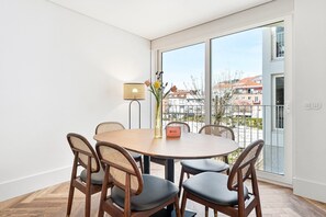 Un coin repas avec une table ronde, quatre chaises, un vase de fleurs et une lampe.