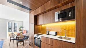 A modern kitchen with wooden cabinetry, a built-in microwave, a toaster, and a sink. - GuestReady - Santa Barbara Garden House 32 (Braga)