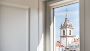 Una ventana con vista a un edificio histórico y una torre de campanas.