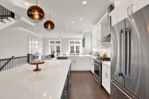 A modern kitchen with a large island, stainless steel appliances, and pendant lighting. - Luxury Riverfront Retreat in the Eastern Wharf | Heated Pool Access (Savannah)