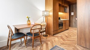 Eine moderne Küche mit Holzschränken, einem Essbereich mit Holztisch und -stühlen sowie einem sichtbaren Mikrowellenherd.