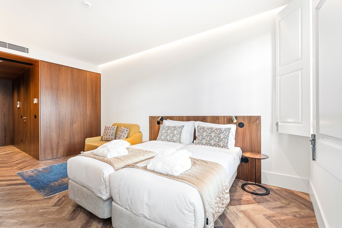 Habitación de hotel con cama doble, sofá, una mesita pequeña y armario de madera.
