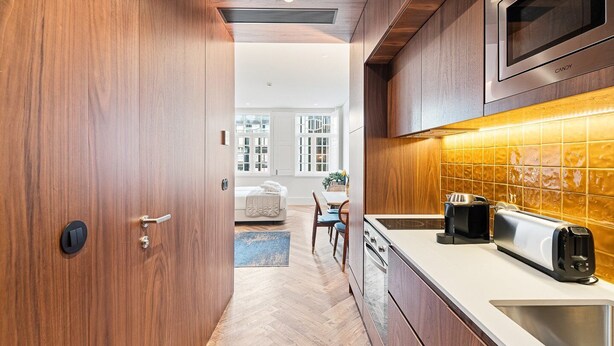 Eine moderne Küche mit Holzausstattung, einer Mikrowelle, einem Toaster und einem Essbereich mit Tisch und Stühlen.