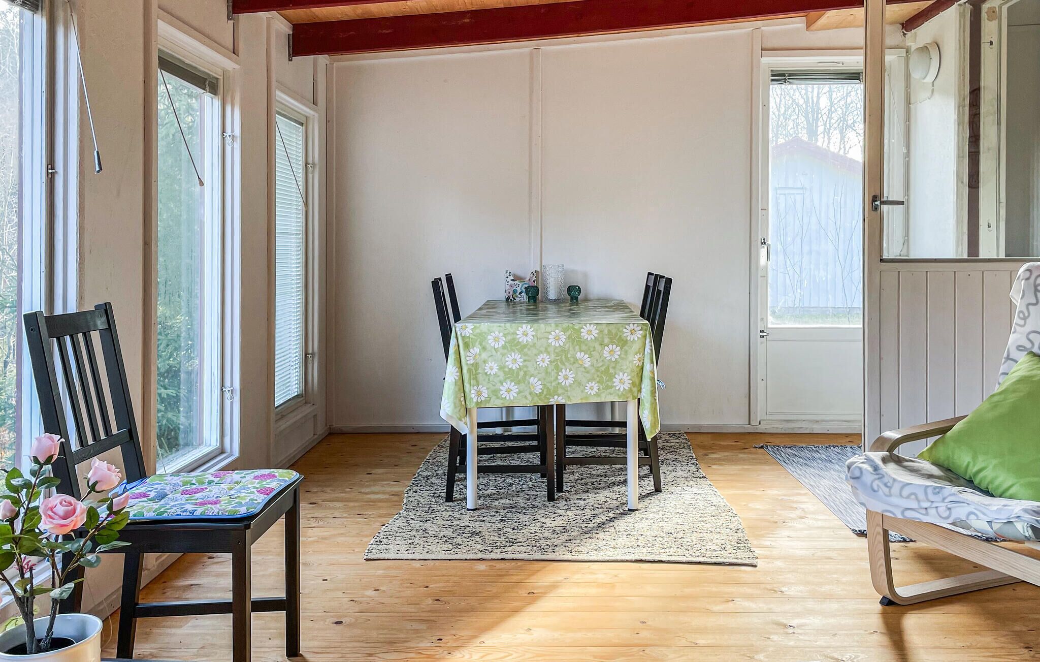 A dining area with a table, chairs, a rug, and a chair with a cushion.