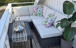 A white outdoor sofa with floral cushions, a checkered table, and a potted plant. - Awesome home in Hamburgsund with WiFi (Hamburgsund)