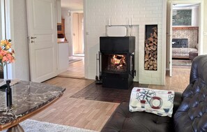 A living room with a fireplace, a sofa, a coffee table, and a door leading to another room. - Awesome home in Hamburgsund with WiFi (Hamburgsund)