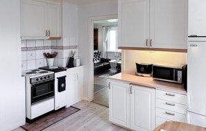 A compact kitchen with white cabinetry, a stove, oven, microwave, and a coffee machine. - Awesome home in Hamburgsund with WiFi (Hamburgsund)
