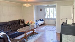 A living room with a dark brown leather sofa, a marble coffee table with a vase of flowers, a wooden door, and a black appliance on the right. - Awesome home in Hamburgsund with WiFi (Hamburgsund)