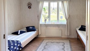 A small room with two single beds, a window with curtains, a radiator, and a wall clock. - Awesome home in Hamburgsund with WiFi (Hamburgsund)