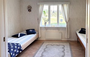 A small room with two single beds, a window with curtains, a radiator, and a wall clock. - Awesome home in Hamburgsund with WiFi (Hamburgsund)
