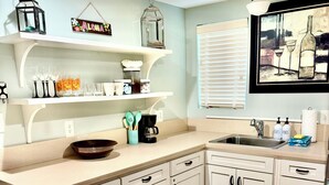 A kitchen with white cabinets, a wooden countertop, a coffee maker, and a window with blinds. - Walking distance to the Beach! 2 kitchens! Ground floor access! (Galveston)