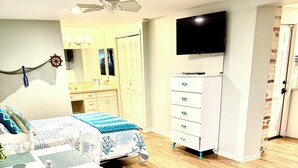 A room with a bed, a TV, a desk, and a chair. - Walking distance to the Beach! 2 kitchens! Ground floor access! (Galveston)