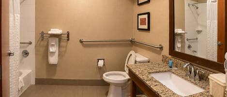 A hotel bathroom with a toilet, bidet, sink, and handrails.