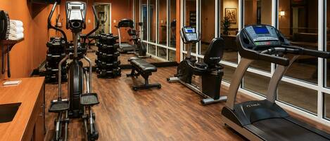 A gym with cardio machines, weight stations, and a bench.
