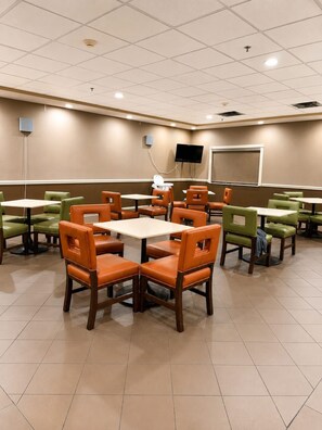 A conference room with multiple tables and chairs, a projector screen, and a television. - HOTELWORLD INN & SUITES (Corbin)