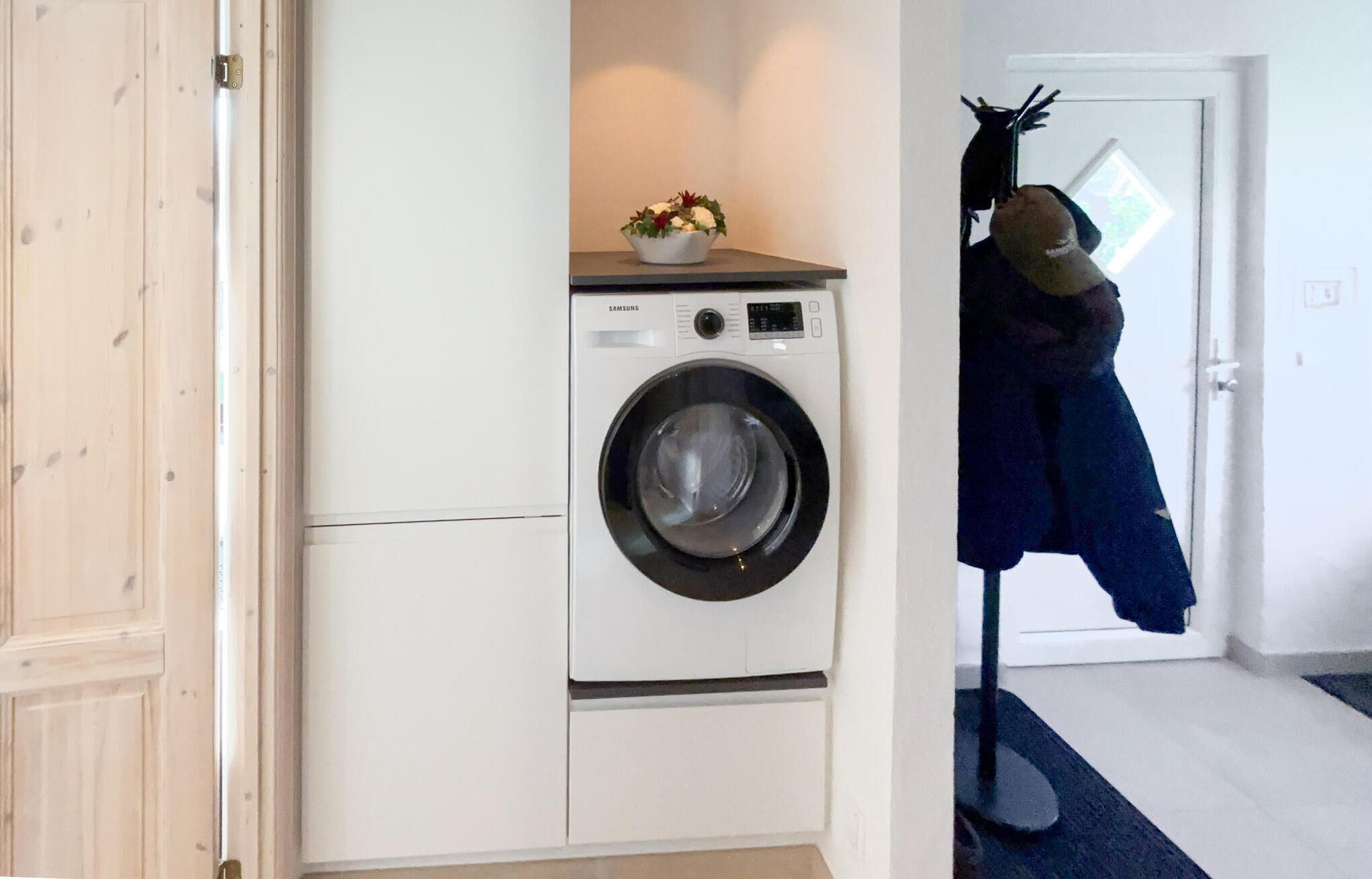 Un espace buanderie comprenant un lave-linge, un porte-manteau et une porte.