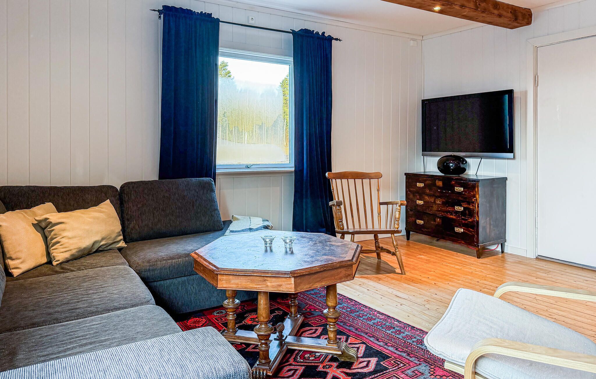 A living room with a sofa, a coffee table, a TV, and a wooden cabinet.