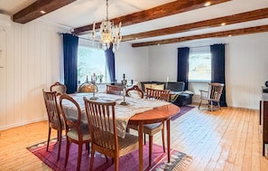 Un comedor con mesa de madera, sillas, candelabro y sofá.
