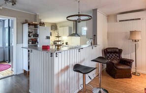 Una cocina con barra, una silla de cuero marrón y una lámpara de pie alta.