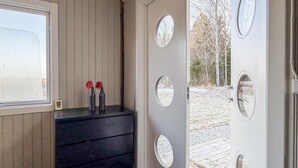 Een houten interieur met een raam, een donkere bank en een deur met ronde glaspanelen.