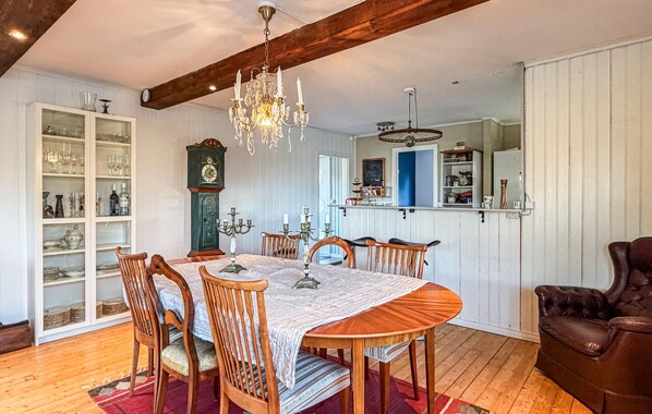 Ein Esszimmer mit Holztisch, Stühlen, einer Chandelier, einer Uhr und einem Schrank mit Glastüren.