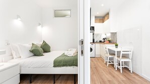 A modern hotel room with a bed, a small desk, a washing machine, and a dining area. - GuestReady - Cosy retreat in Porto's Campanhã (Campanhã)