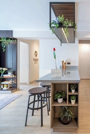 A modern kitchen with a central island, bar stools, and a variety of potted plants. - Luxury Boutique Apt | Miraflores | Ocean View (Miraflores)