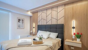 Een moderne slaapkamer met een bed, nachtkastje, wandplank en een bedlampje.