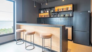 Een moderne keuken met een bar, een zwarte betegelde spatwand en houten krukken.