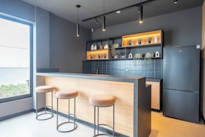 A modern kitchen with a bar area, black tiled backsplash, and wooden stools. - Premium Apartment with pool in Larco, Miraflores. (Miraflores)