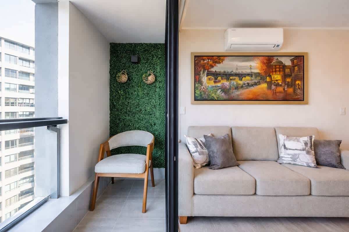 A balcony with a chair, a green wall, and a painting of a street scene.