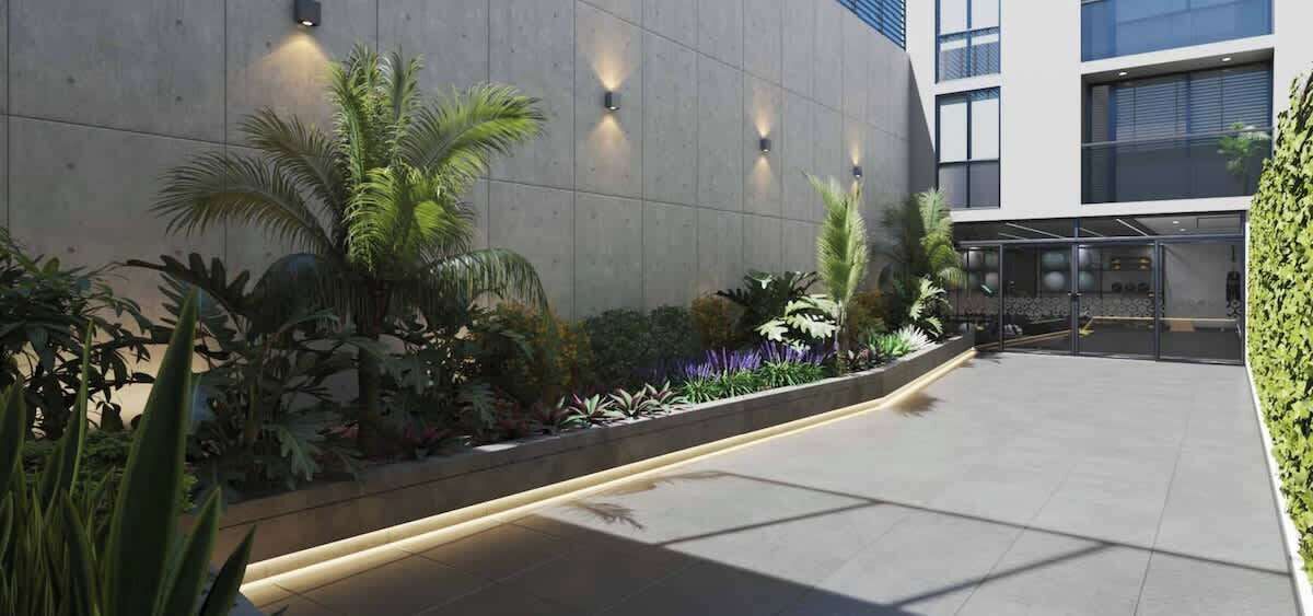 Un bâtiment moderne avec une façade contemporaine, une cour dallée, des plantes en pot et une entrée en verre.