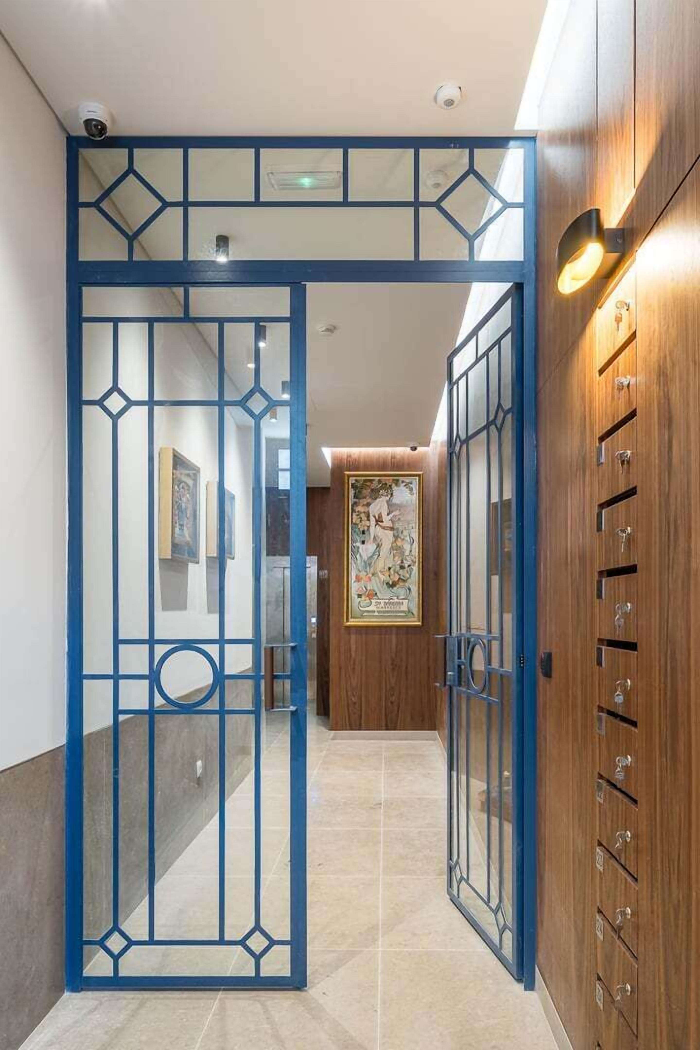 Un couloir agrémenté d’une porte décorative bleue, de meubles en bois et d’une œuvre d’art encadrée au mur.