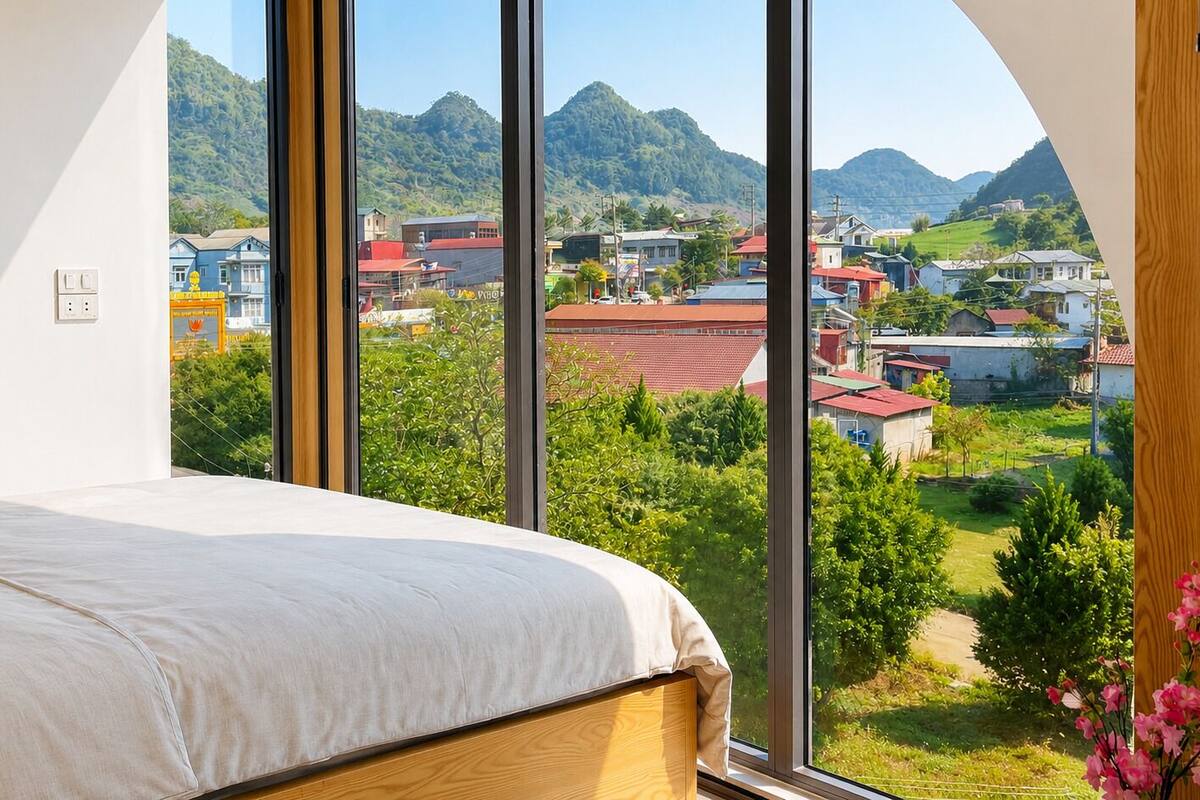 Een slaapkamer met een groot raam, een bed en uitzicht op een stad en bergen.