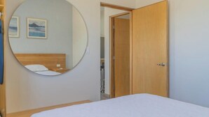 A bedroom with a bed, a round mirror, a wooden door, and a hallway leading to another room. - Pool, BBQ & a Short Walk to the Malecon (La Paz)