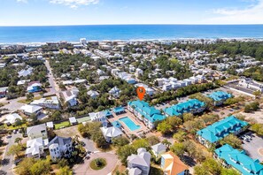 An aerial view of a coastal residential area with a large hotel featuring a swimming pool and blue-roofed buildings. - Awesome 4 Bedroom overlooking Pool / Easy Beach Access (Santa Rosa Beach)