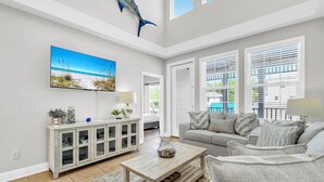A spacious living room with a large TV, a cabinet, a sofa, and a coffee table. - Awesome 4 Bedroom overlooking Pool / Easy Beach Access (Santa Rosa Beach)