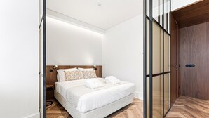 Una camera da letto moderna con un letto, un comodino, una testiera in legno e una porta scorrevole.
