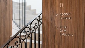 A wooden door with directional arrows pointing to amenities: rooms, lounge, pool, gym, and laundry. - GuestReady - Santa Barbara Garden House 13 (Braga)