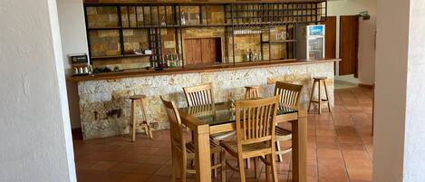 A bar area with a stone wall, wooden chairs, and a tiled floor.