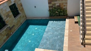 Una piscina con bordo piastrellato, una piccola area relax e una scala.